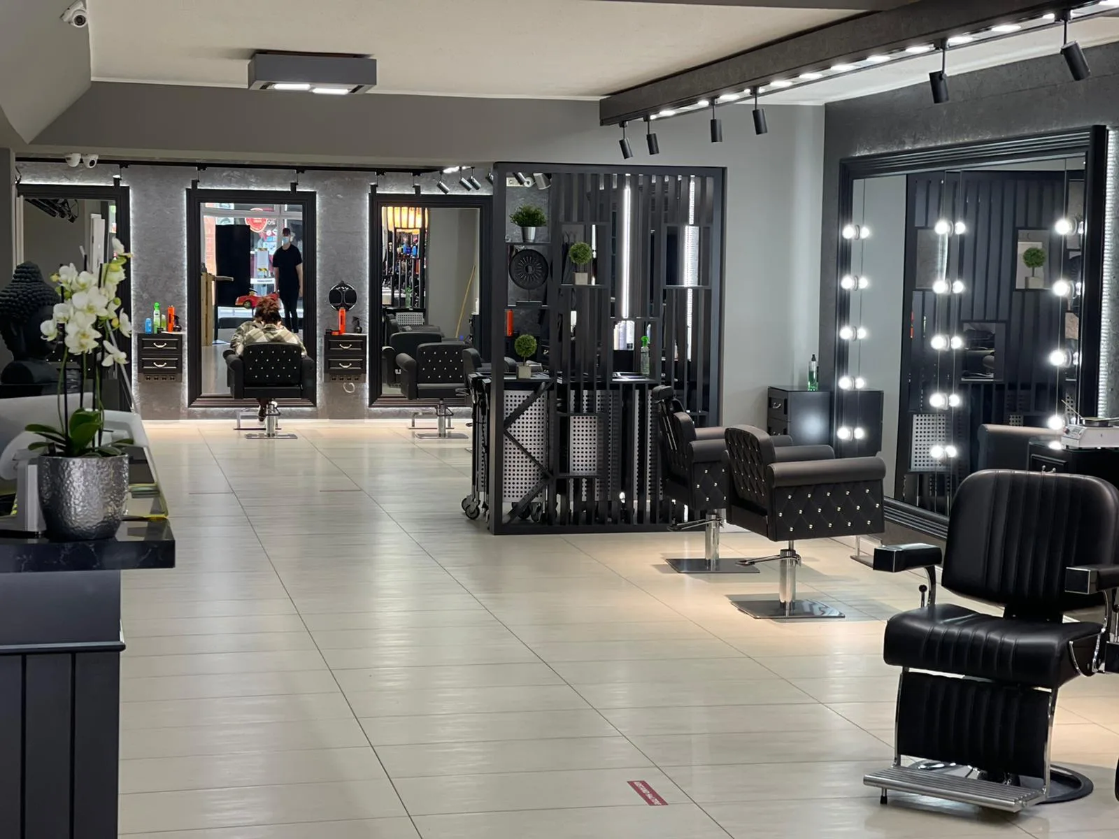 Arbeitsplätze im Haarstudio Außergewöhnlich mit beleuchteten Spiegeln und schwarzen Friseurstühlen
